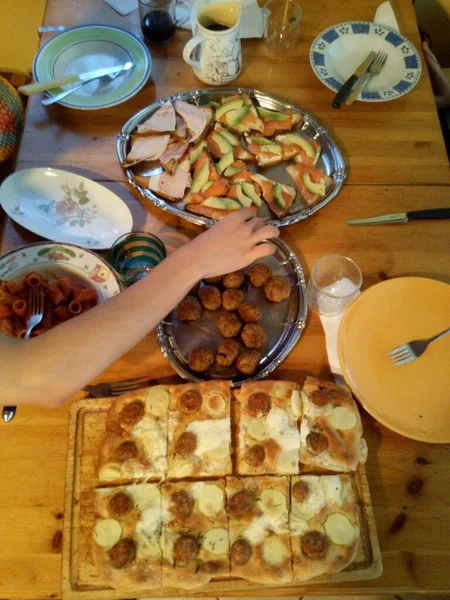 Een man neemt een fingerfood van een tafel vol met hapjes — Stockfoto