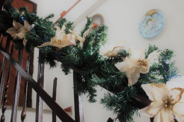 Noel için süslenmiş özel bir evde çam ağacından sallanan ışıklar ve beyaz çiçeklerle dolu bir merdivenin derisini yüzün.