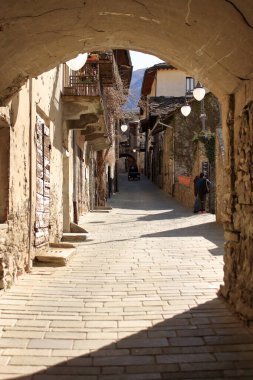 Anne ve oğul İtalyan Alplerinde küçük bir köyün caddelerinde yürüyorlar.