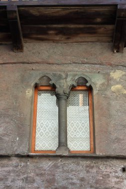 Bir dağ köyünde taş sütunlu Gotik tarzı bir pencere.