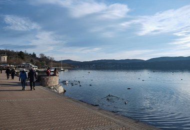 Viverone Gölü, İtalya - Şubat 2021: İnsanlar bir bahar günü Alp Gölü 'nün rıhtımında gezinirler.