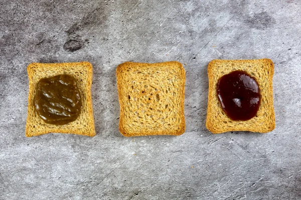 Drei Zwieback-Scheiben unterschiedlich ausgekleidet, weil mit verschiedenen Marmeladen — Stockfoto