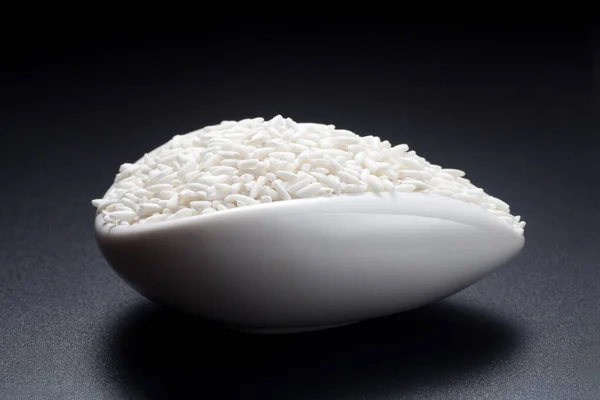 Glutinous rice in a ceramic spoon on black background.