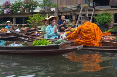 Ratchaburi, Tayland - 18 Eylül 2020: Damnoen Saduak Yüzen Pazarı 'ndaki keşişe sadaka veren ahşap tekne tüccarı, tekneyle gezen turistler Tayland kanallarında popüler bir turizm merkezidir..