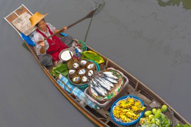 Ratchaburi, Tayland - 18 Eylül 2020: İnsanlar Damnoen Saduak Yüzen Pazarında ahşap teknede Tayland mutfağı satıyorlar. Tekneyle gezen turistler Tayland kanallarında popüler turistik ilgi odağıdır..