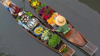 Ratchaburi, Tayland - 18 Eylül 2020: İnsanlar Damnoen Saduak Yüzen Pazarında ahşap teknede Tayland mutfağı satıyorlar. Tekneyle gezen turistler Tayland kanallarında popüler turistik ilgi odağıdır..