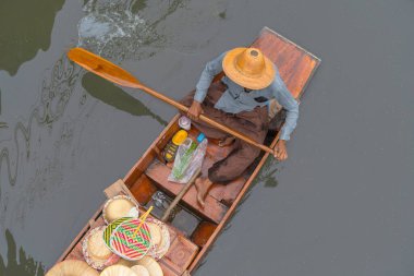 Ratchaburi, Tayland - 18 Eylül 2020: İnsanlar Damnoen Saduak Yüzen Pazarında ahşap teknede Tayland mutfağı satıyorlar. Tekneyle gezen turistler Tayland kanallarında popüler turistik ilgi odağıdır..