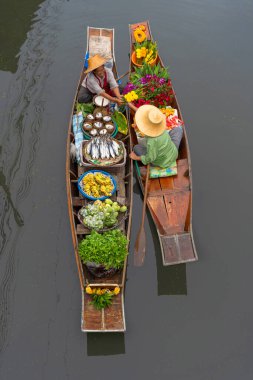 Ratchaburi, Tayland - 18 Eylül 2020: İnsanlar Damnoen Saduak Yüzen Pazarında ahşap teknede Tayland mutfağı satıyorlar. Tekneyle gezen turistler Tayland kanallarında popüler turistik ilgi odağıdır..