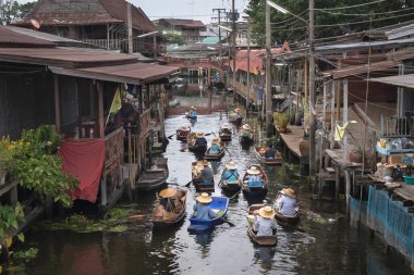 Ratchaburi, Tayland - 18 Eylül 2020: İnsanlar Damnoen Saduak Yüzen Pazarı 'ndaki ahşap teknede tarım meyvesi ve yiyecek satıyorlar..