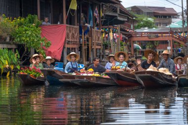 Ratchaburi, Tayland - 18 Eylül 2020: İnsanlar Damnoen Saduak Yüzen Pazarı 'ndaki ahşap teknede tarım meyvesi ve yiyecek satıyorlar..