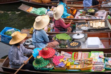 Ratchaburi, Tayland - 18 Eylül 2020: İnsanlar Damnoen Saduak Yüzen Pazarında ahşap teknede Tayland mutfağı satıyorlar. Tekneyle gezen turistler Tayland kanallarında popüler turistik ilgi odağıdır..