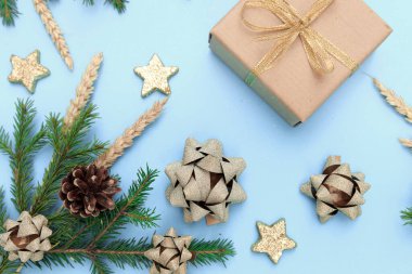 Noel hediyesi olarak arkaplanda kozalaklı dallar ve Noel oyuncakları var. Mesaj için bir yer. Yeni yıl gökyüzü mavi arkaplan, tavşanlı ve yıldızlı altın süslemeler..