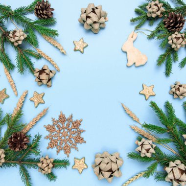 Noel, kozalaklı dalları ve Noel oyuncaklarıyla gökyüzü mavisi arka plandaki kompozisyonun düzeni. Yeni yılın arka planında altın süslemeler, yaylar, koniler, buğday dikenleri ve yıldızlarla