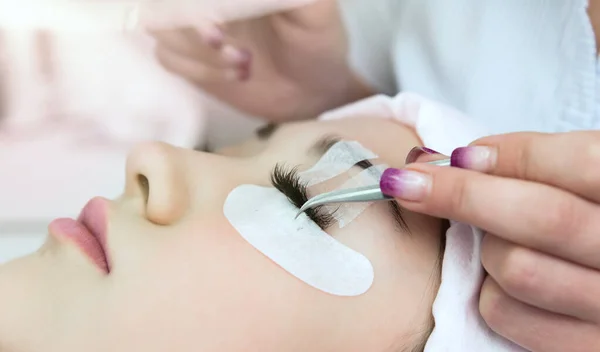 Kirpik uzatma prosedürü. Uzun kirpikli kadın gözü. Güzel genç kız kirpik uzantıları.