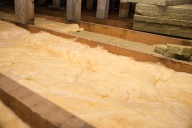 Tavanda fiberglasla yalıtım. Soğuğa karşı bir bariyer için taş yünü ve fiberglas yalıtım malzemesiyle kaplama ve yalıtım. Konforlu ekonomik konut kavramı.