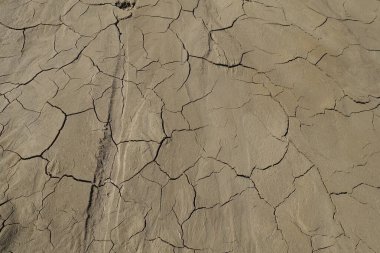 Çatlak toprak zemin dokusu. Islak çamur toprak ve kum mozaik deseni, üst görünüm