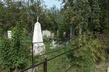 Eski mezarlık. Mezarlar ve anıtlar, çimen ve ağaçlarla kaplanıp bükülür. Rusya, Krasnoyarsk, Badalyksk Mezarlığı, 21 Ekim 2020