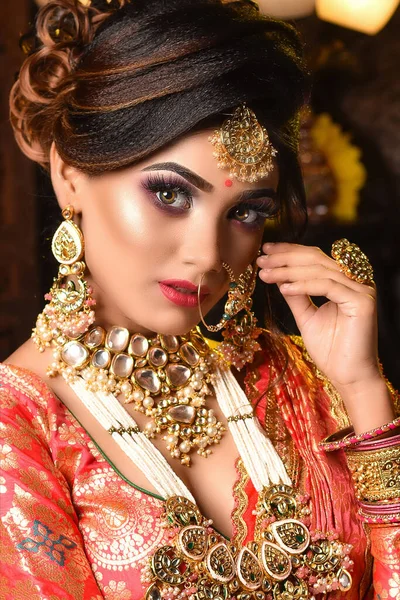 Close up Portrait of very beautiful young Indian bride in luxurious bridal costume with makeup and heavy jewellery in studio lighting indoor. Wedding fashion.