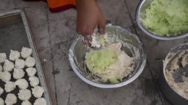 Hintli kadın güneşli bir günde bir kasede Daler Bori karışımı hazırlıyor. Bengali mutfağında popüler olan bir çeşit kurutulmuş mercimek köftesi..