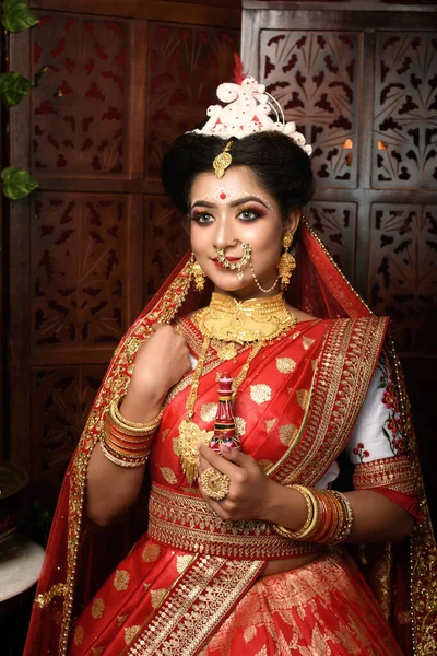 Portrait of very beautiful Indian bride holding traditional wooden sindur or sindoor box in hand, Wedding symbol sindoor box. Wedding Lifestyle and Fashion.