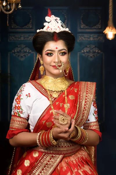 穿着印度教红色传统婚纱 绣有黄金珠宝 头戴面纱的印度新娘在室内灯光下温柔地微笑着 孟加拉族婚礼 — 图库照片