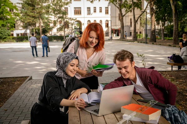 Genç öğrenciler birlikte çalışır, sohbet eder, bilgisayara bakar, film izler ve okulun bahçesinde gülerler. Üniversite, kampüs, okul bahçesi, Müslüman öğrenci, Hıristiyan, Yahudi, farklı insanlar.