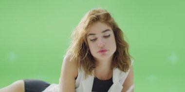 Siyah mayo ve beyaz gömlekli, yeşil arka planda dinlenen güzel genç bir kadının görüntüleri.