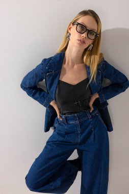 Kot elbise, deri bluz ve gözlük giyen modaya uygun şık bir kadının beyaz arka plana karşı güvenle poz verdiği yakın plan portresi. Modern moda, güzellik, yaşam tarzı ve kopyalama alanı.