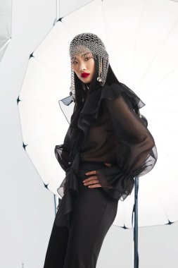 Kristal bir başlık ve siyah bir elbise giyen zarif bir kadının moda stüdyosu portresi, profesyonel ışıklandırma, gösterişli lüks, cazibe ve özel tasarım tarzı ile güven içinde poz veriyor..