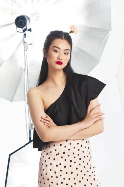 Beyaz arka planda softbox ışıklandırması olan profesyonel fotoğraf stüdyosunda kendine güvenen manken, modern tarz, güzellik, zarafet ve son moda konseptini sergiliyor..