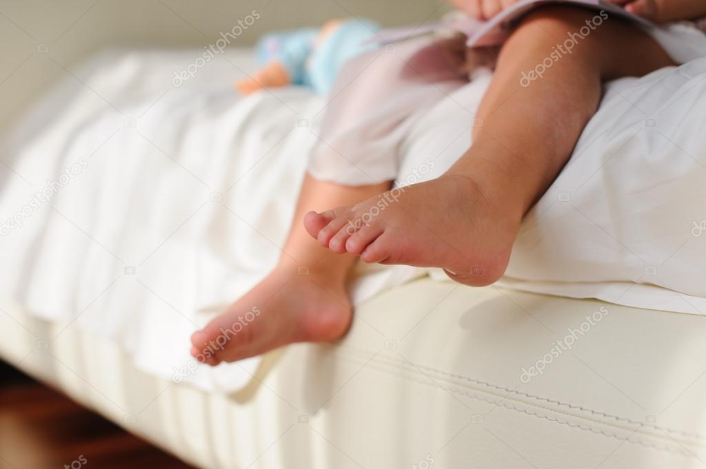 Children's bare feet,  sitting on bed