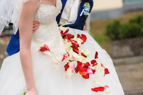 Pétalas de rosa em um vestido de casamento — Fotografia de Stock
