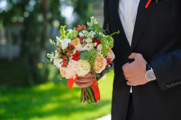 Ženich v obleku drží krásné květiny kytice — Stock fotografie