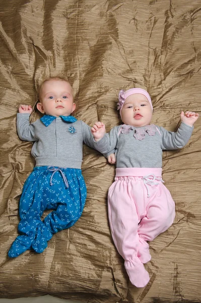 Two babies lying on bad and grimacing — Stock Photo, Image