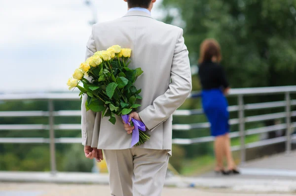 Человек прячет букет цветов за спиной — стоковое фото