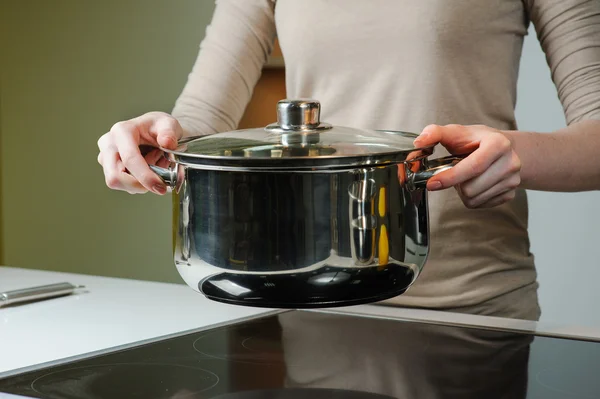 Mulher segurando uma panela de molho em sua cozinha — Fotografia de Stock