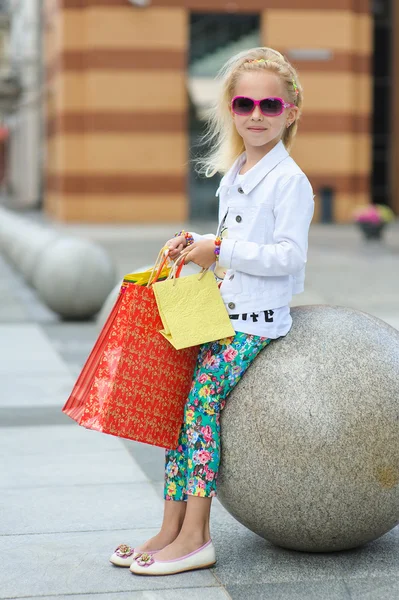 Модно одетая маленькая девочка с сумками для покупок — стоковое фото