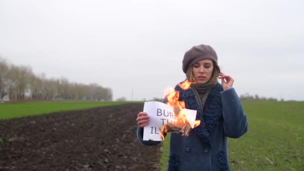 Junge Frau verbrennt das Illusionspapier im Freien — Stockvideo