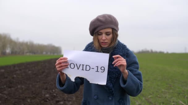 Vrouw houvast papier met gedrukt woord Covid-19 — Stockvideo