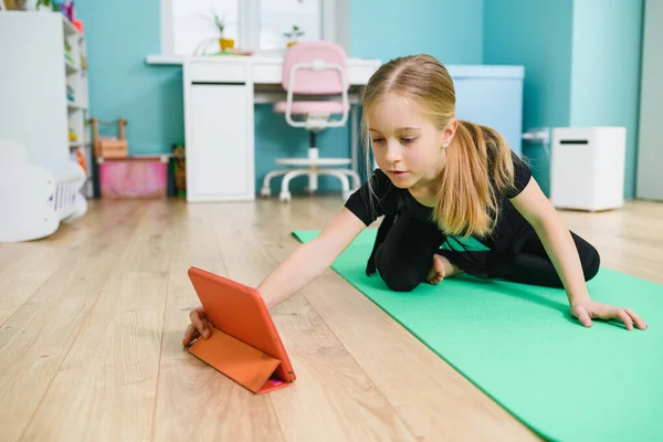 女の子はオンラインスポーツレッスンの前にタブレットを準備 — ストック写真