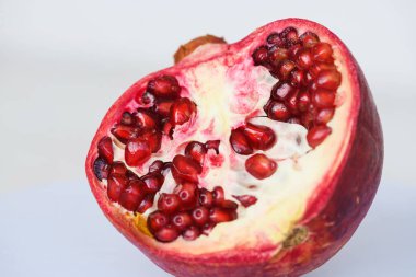 Kabuklu ve tohumlu olgun nar çekirdeğinin yarısı izole edilmiş, sağlıklı besin ve içecek içeriyor.