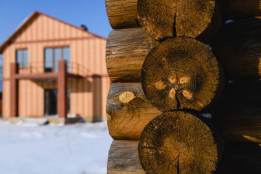 Köy evindeki ahşap kulübelerin yuvarlak kütükleri kışın, kırsal arka planda kapanıyor.