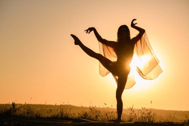 Sıcak güneş ışığında dans eden kız silueti şeffaf kumaşla, kadın vücudunda kıvrımlar, açık havada hareketlilik.