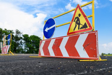 Yoldaki yol çalışması tabelası. Yol işaretlerinin tamiri ve mavi gökyüzünün arka planında bir baypas oku.