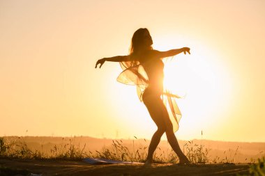 Sıcak güneş ışığına karşı dans eden kadın silueti