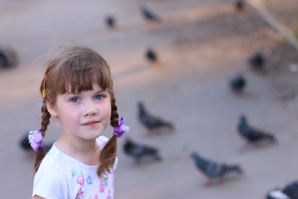 Little pretty girl with pigtails smiles and looks at camera — Stock Photo, Image