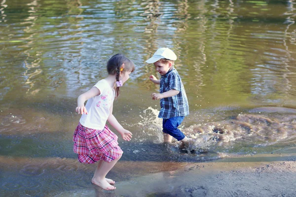 Naboso holčička s chlapcem se smát a běh ve vodě rybníka — Stock fotografie