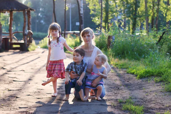 Happy mother with three little barefoot children pose in summer — Stock Photo, Image