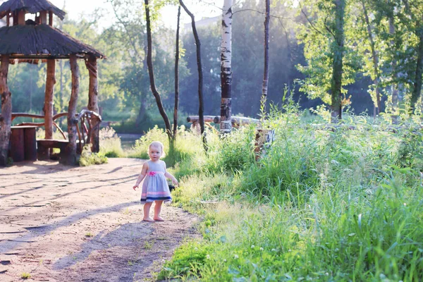 Mutlu elbiseli küçük yalınayak kız yaz güneşli parkta duruyor — Stok fotoğraf