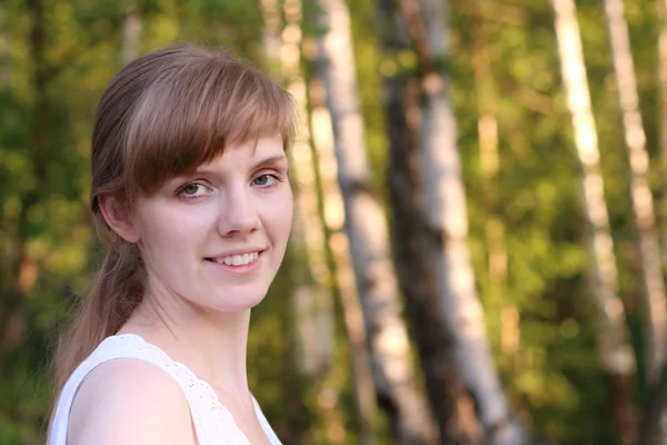 Красивая молодая женщина в белых улыбках в солнечном летнем парке — стоковое фото